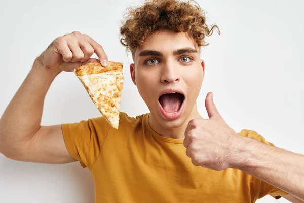 잘생긴 남자가 피자를 먹으면서 밝은 배경을 포즈를 취하고 있습니다. — 스톡 사진