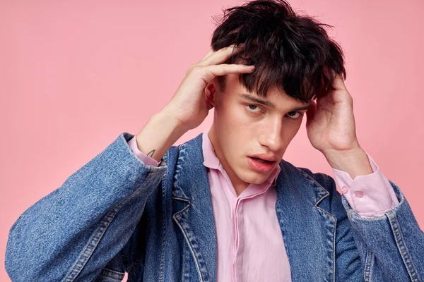 Красивий чоловік в молодіжному стильному одязі джинсова куртка, що позує рожевий фон незмінним — стокове фото