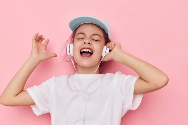 Retrato de felices auriculares de niña sonriente en una camiseta blanca y una gorra Estilo de vida inalterable — Foto de Stock