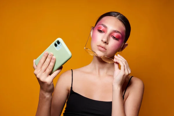 Mulher elegante olha para o telefone maquiagem brilhante posando emoções da moda isolado fundo inalterado — Fotografia de Stock