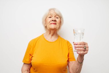 Neşeli yaşlı kadın elinde bir bardak su ışığı arka planında