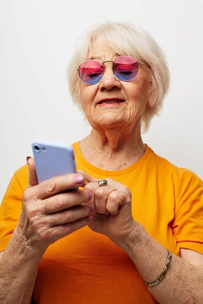 노란 티셔츠를 입은 나이든 친절 한 여자가 전화 감청 감정으로 대화를 나누는 모습 — 스톡 사진