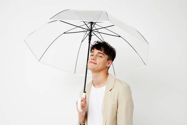 ファッションライトの背景を変えることなくポーズをとる傘を持っている若い男 — ストック写真
