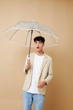 Açık şemsiyeli yağmurluk giymiş ceketli bir adam.