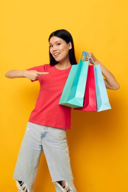 Kırmızı tişörtlü Asyalı alışveriş çantalı kadın. Arka planı değiştirilmemiş.