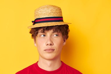 Kırmızı kıvırcık saçlı, kırmızı tişörtlü, sarı şapkalı adam.