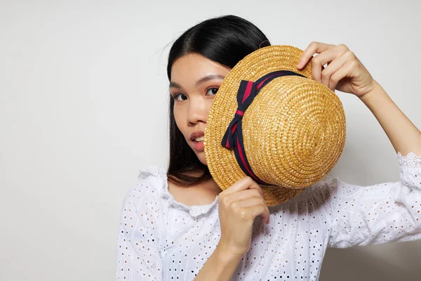 손에는 아름다운 아시아인 여인의 모자를 끼고 아무런 변화가 없는 배경에서 미소를 짓는 모습 — 스톡 사진