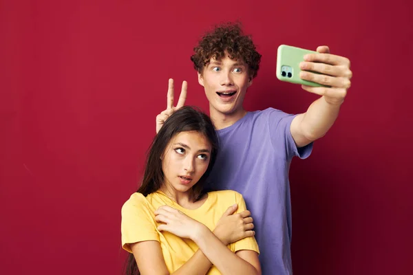 Una giovane coppia in T-shirt colorate con uno sfondo isolato telefono — Foto Stock