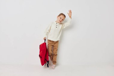 Arka planında şapka olan küçük bir kız okul çantası.