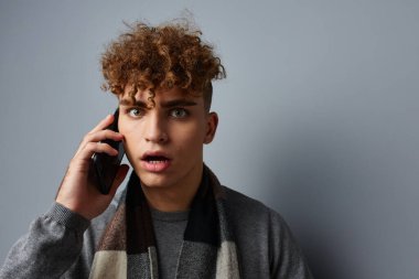 Ekose eşarplı çekici bir adam telefon modasına bakıyor. Yaşam tarzı değişmemiş.