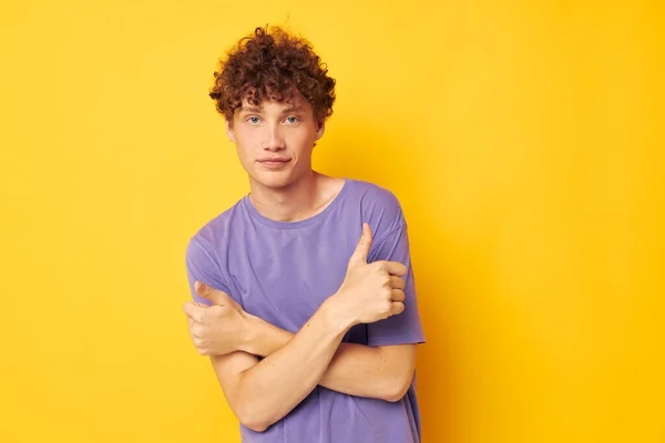 Хлопець з кучерявим волоссям у фіолетових футболках студія жовтий фон — стокове фото