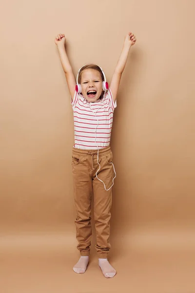 Menina bonita em listrado t-shirt fones de ouvido gesto mãos infância inalterada — Fotografia de Stock