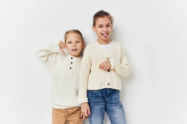 Two little girls in sweaters posing childhood light background — 图库照片