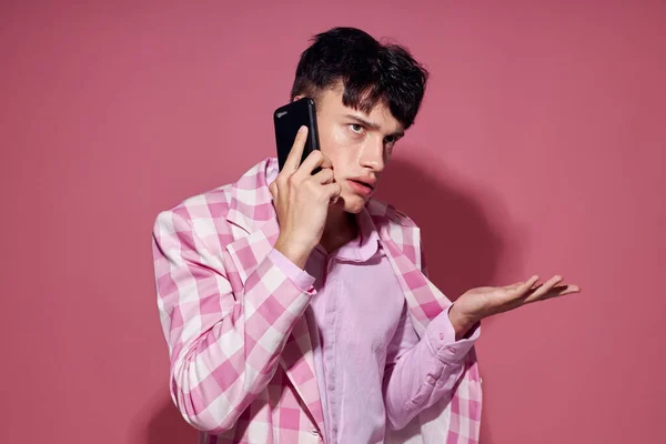 Hombre bonito con un teléfono en la mano chaqueta rosa moda estilo elegante aislado fondo inalterado — Foto de Stock