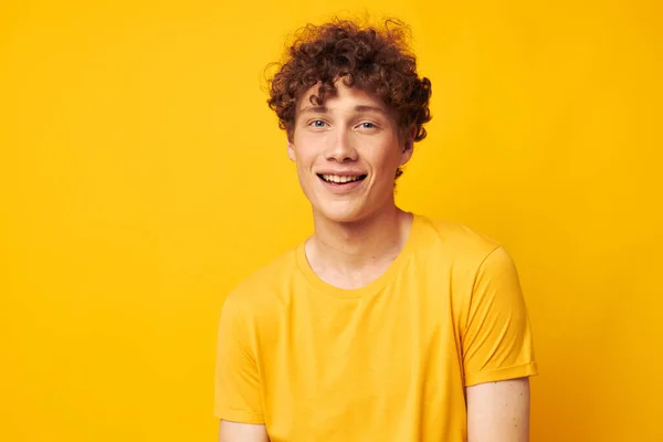 Şık sarı tişört giyen genç bir kıvırcık adamın portresi tek renkli poz veriyor. — Stok fotoğraf
