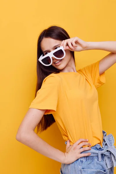 Vacker flicka med långt hår bär solglasögon poserar gul bakgrund — Stockfoto