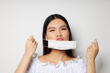 Asya portresi güzel genç kadın medikal maske baş koruma ışık arka planı değiştirilmemiş