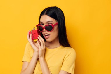 Elinde hediye kutuları olan bir kadın değişmemiş arka plan pozu vererek eğleniyor.