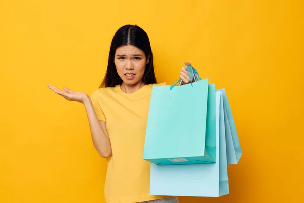 Γυναίκα με ασιατική εμφάνιση με πακέτα στα χέρια ψώνια απομονωμένο φόντο αμετάβλητη — Φωτογραφία Αρχείου