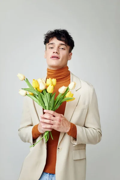 Красивий чоловік у білій куртці з букетом жовтих квітів елегантна модель студія — стокове фото