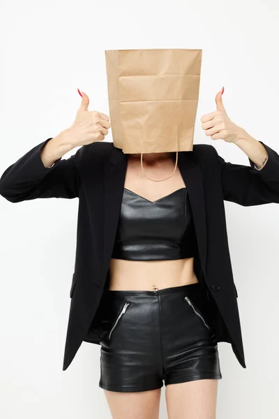 Atraktivní žena s taškou na hlavě v černé bundě červená lak na nehty světlo na pozadí — Stock fotografie