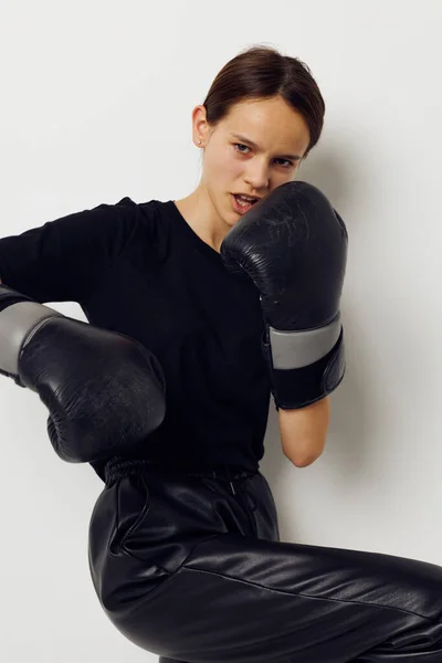 Donna atletica in guanti da boxe in pantaloni neri e una t-shirt sfondo isolato — Foto Stock
