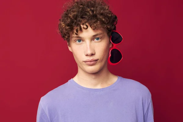 Portrait of a young curly man guy in a purple t-shirt with sunglasses posing Youth style — Zdjęcie stockowe