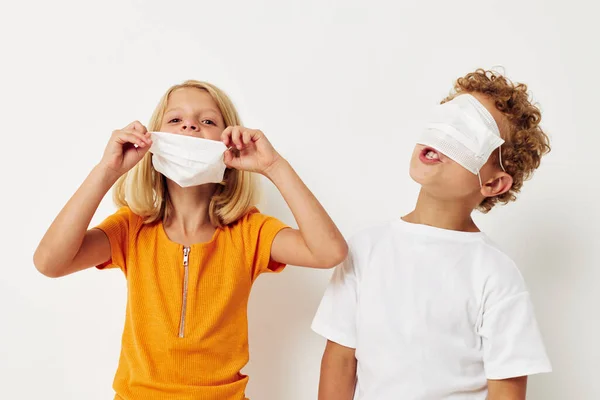 Дві радісні дитини в захисті медичної маски позують похмурий світлий фон — стокове фото