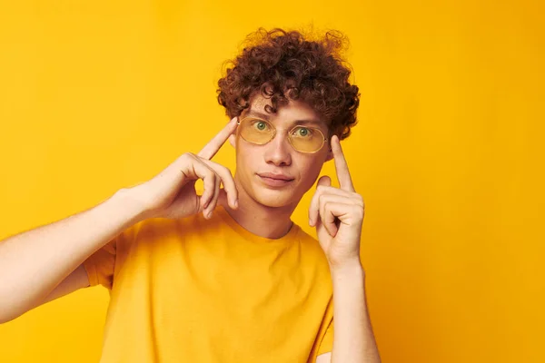 Retrato de un joven rizado hombre amarillo camiseta gafas moda mano gestos monocromo disparo — Foto de Stock