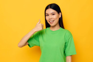 Çekici genç Asyalı kadın yeşil tişörtle poz veriyor. Duygular, fotokopi alanı izole edilmiş arka plan değiştirilmemiş.