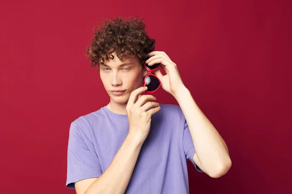 Young curly-haired man hand gestures heart shaped glasses posing isolated background — Stock Photo, Image