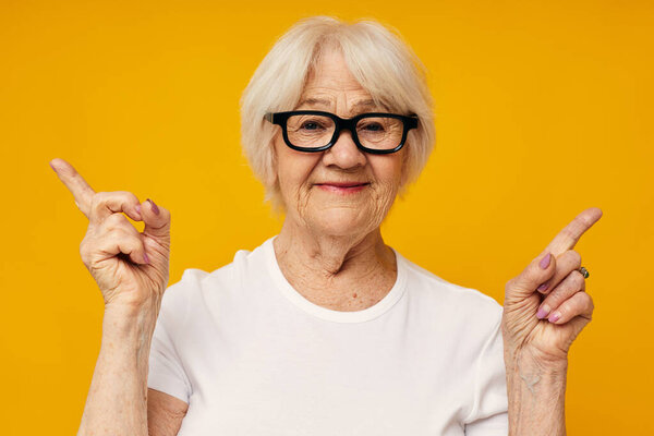 Фото пожилой женщины на пенсии в футболке и очках желтого фона