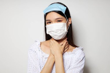 Çekici Asyalı genç kadın tıbbi maske koruması. Geçmişi değiştirilmemiş.