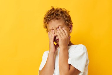 Sarı arka planda beyaz tişörtlü kıvırcık saçlı tatlı çocuk.