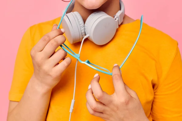 Chica bonita con gafas azules escuchando música en los auriculares fondo rosa inalterado — Foto de Stock