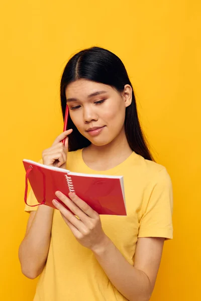 पिवळा टी-शर्ट लाल नोटबुक प्रशिक्षण स्टुडिओ मॉडेल मध्ये आशियाई देखावा असलेली स्त्री अनियंत्रित — स्टॉक फोटो, इमेज
