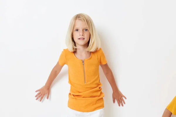 Маленькая девочка с светлыми волосами в желтой футболке на изолированном фоне — стоковое фото