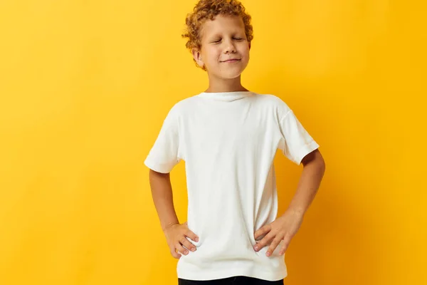 Chłopiec z kręconymi włosami w białej koszulce na żółtym tle — Zdjęcie stockowe