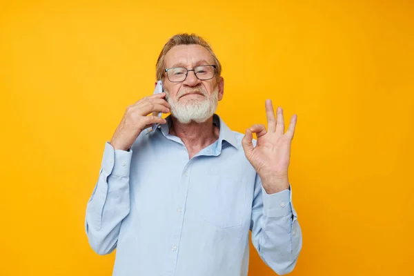 Porträtt äldre man talar på telefonen känslor gul bakgrund — Stockfoto