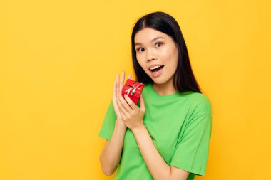 Küçük bir hediye kutusu olan yeşil tişörtlü çekici Asyalı kadın. Değişmemiş yaşam tarzı.