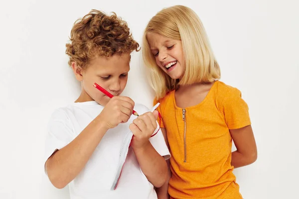 Мальчик и девочка весело в красочных футболках с блокнотом изолированный фон без изменений — стоковое фото