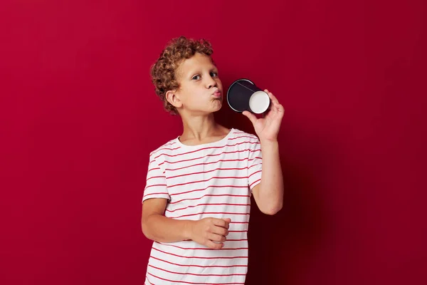 Niño de pelo rizado con una camiseta a rayas con un vaso desechable — Foto de Stock