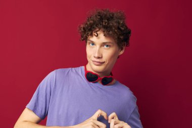 Kırmızı kıvırcık saçlı, yaz tarzı güneş gözlüklü, izole edilmiş bir arka planı var.