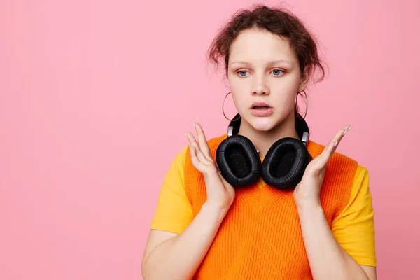 Bela mulher em um suéter laranja fones de ouvido música entretenimento rosa fundo inalterado — Fotografia de Stock