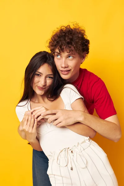 Adolescents embrasser ensemble antics fond jaune inchangé — Photo