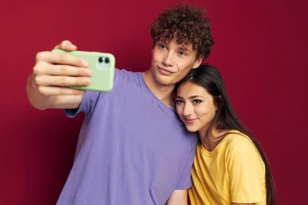 Uomo e donna in T-shirt colorate con uno sfondo isolato telefono — Foto Stock