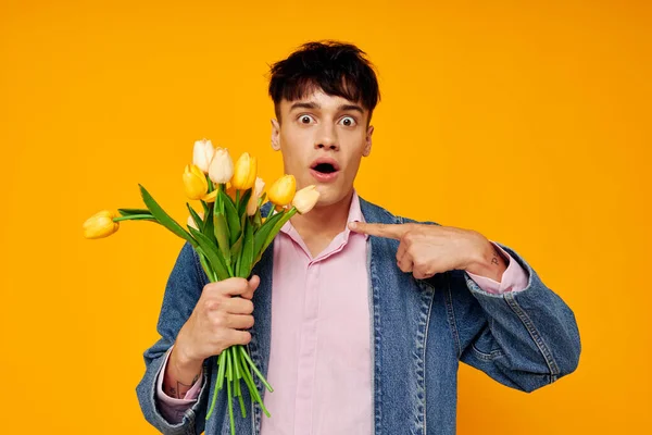 Chico joven en chaqueta de mezclilla con un ramo de flores posando romance — Foto de Stock