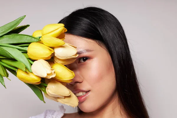 젊은 아시아 여성의 마음 을사로 잡는 꽃은 아무런 변화 없이 독특 한 배경을 배경으로 한다 — 스톡 사진