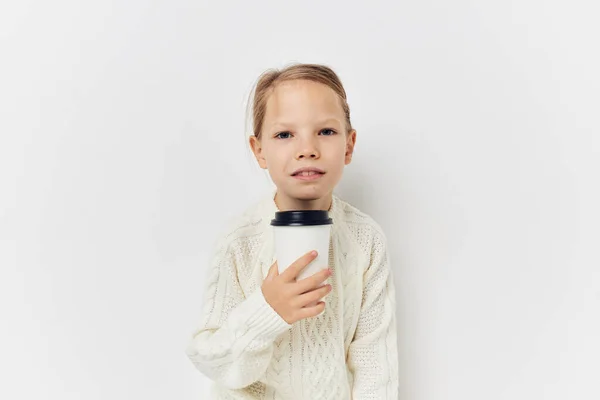 Little girl in white sweater glass with drink light background — Foto Stock