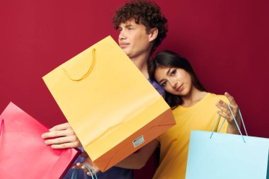 Bir erkek ve kadın portresi Renkli çantalar alışveriş eğlenceli kırmızı arka plan değiştirilmemiş